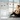 Mujer sonriendo sentada en una esterilla de yoga con un teléfono móvil en la mano, junto a pesas moradas y una balanza inteligente BOMIDI en el suelo.